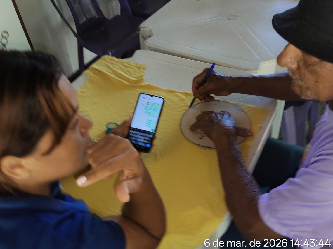 Participante desenhando molde em tecido durante oficina